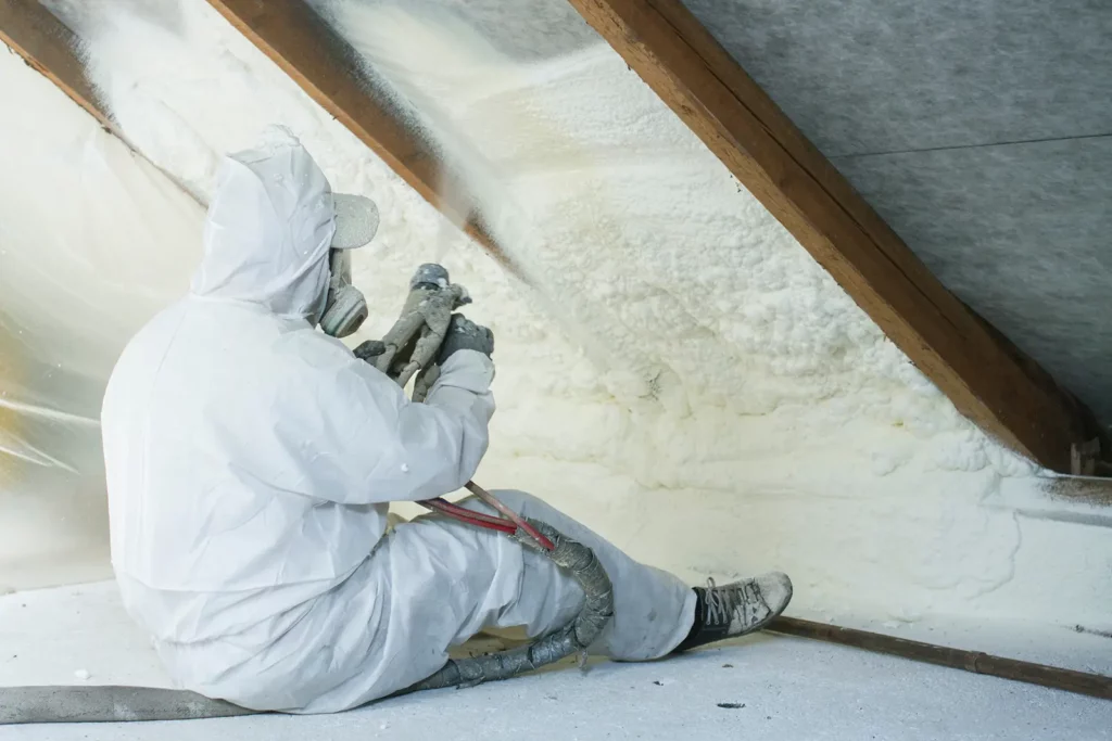 Worker applying spray foam insulation, one of the Energy-Saving Commercial Roof Insulation types