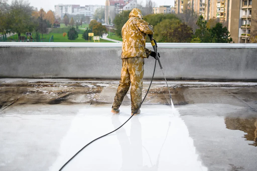 Worker cleaning roof of a building as part of 13 Key Tips for Industrial Roofing System Upkeep