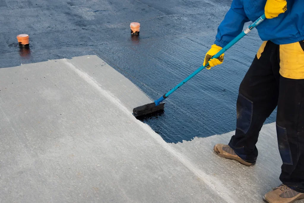 Worker applying bimuten coat on roof top, one of the top 7 Commercial Roofing Installation Techniques