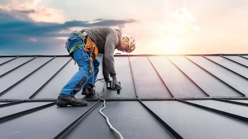 Roofer working on a metal roof with a safety harness on. What Are Your Other Options for Commercial Roofing Safety?