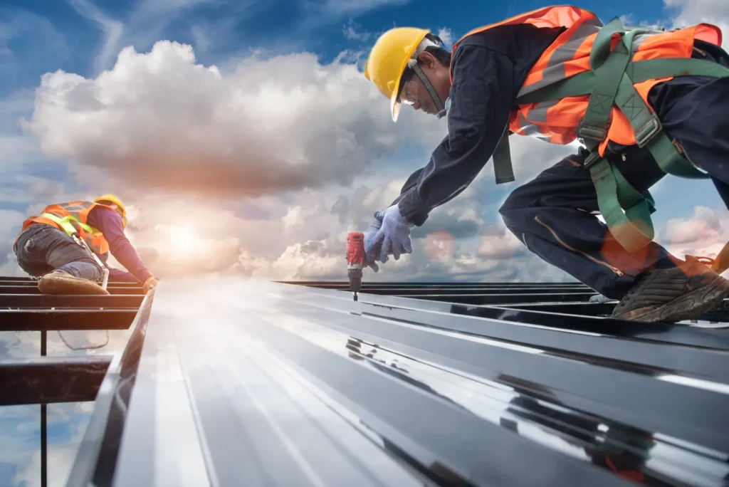 Roof Leak Emergencies. worker builder with hand drill at metal profile roof installation Metal roof construction