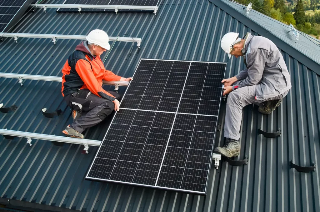 Workers installing solar panels, which is great sustainable tech for commercial roofing.