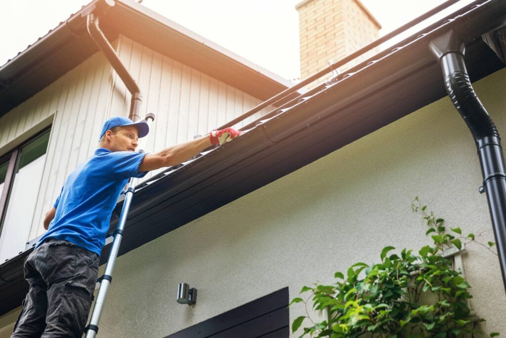 Person inspecting roof with ladder.