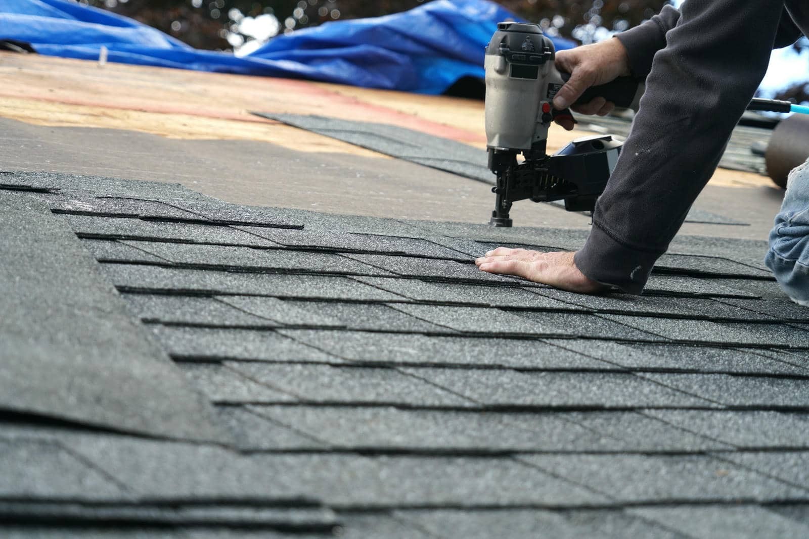 Person installing shingles on a roof