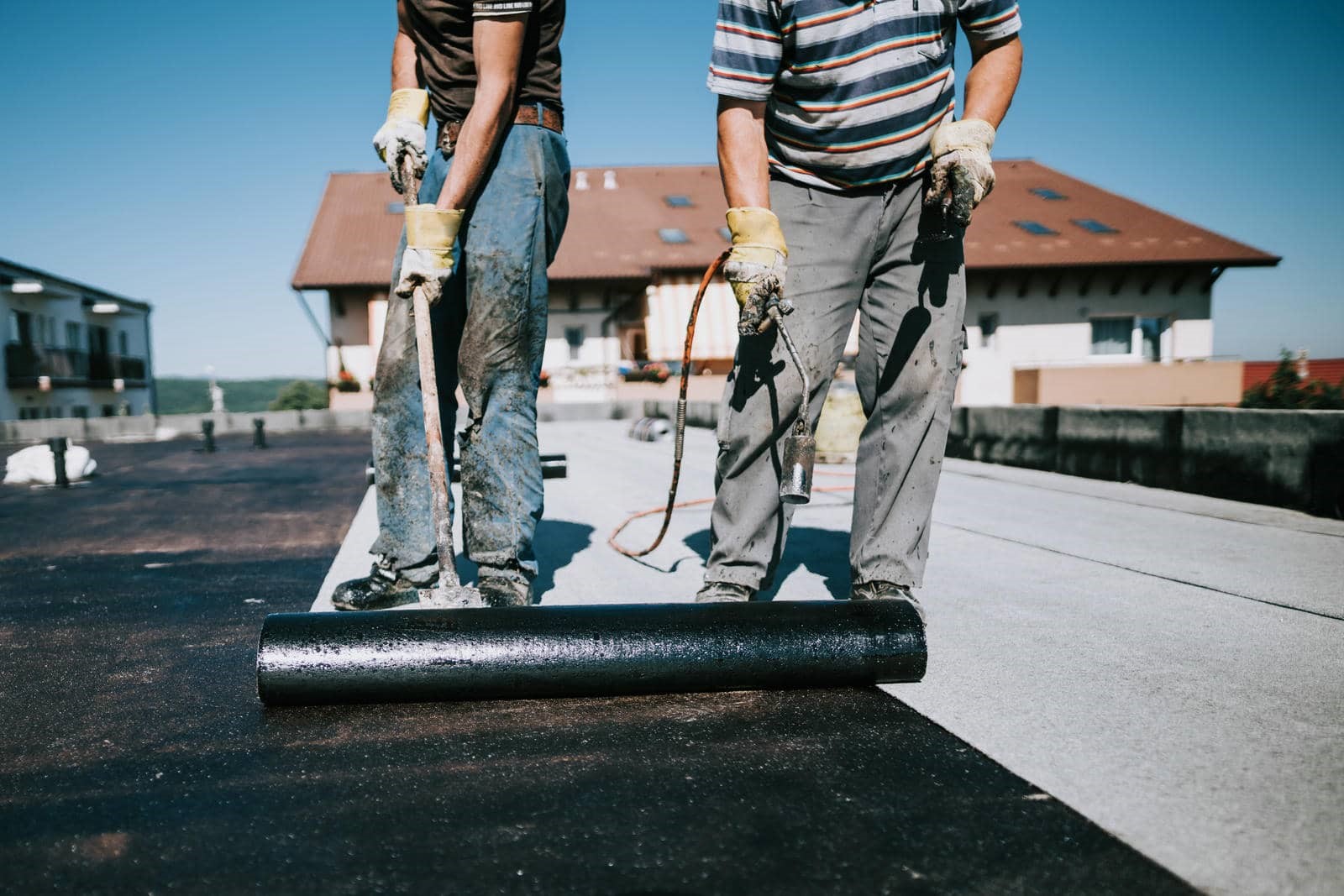 Two workers installing roofing material.