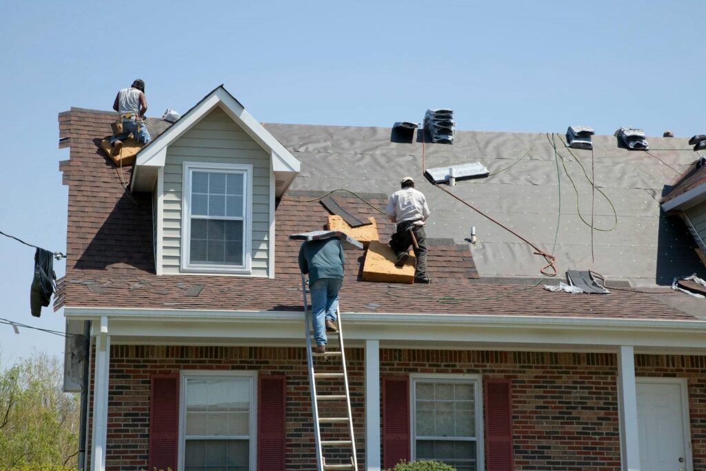 Workers installing shingles on roof