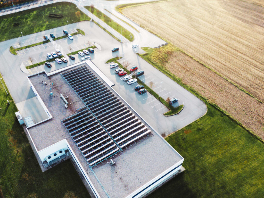 Overhead view of an industrial building with solar panels.|A picture of a Commercial Roofing on a building.