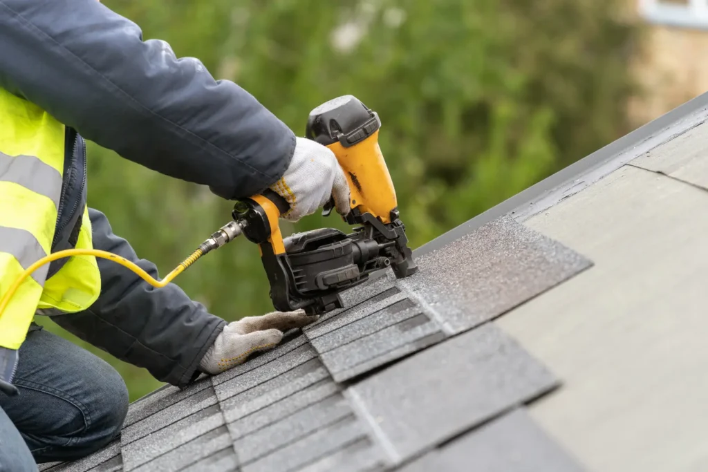 Closeup of a worker installing asphalt shingles