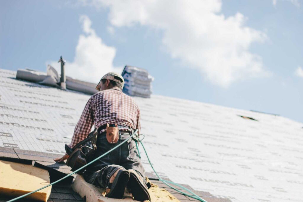 Professional roofer putting shingles on a roof.|Picture of a carpenter working on a roof.