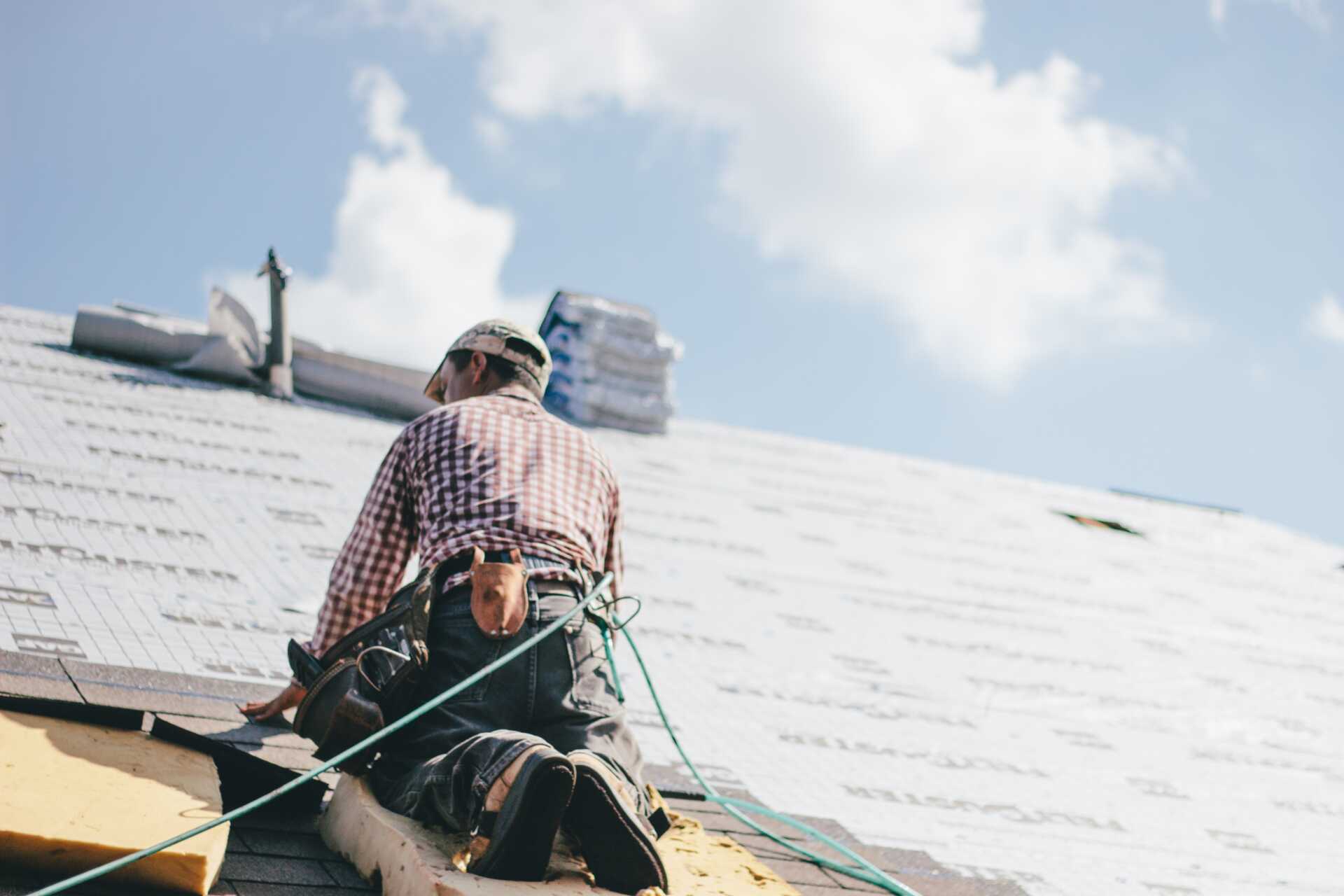 Professional roofer putting shingles on a roof.|Picture of a carpenter working on a roof.